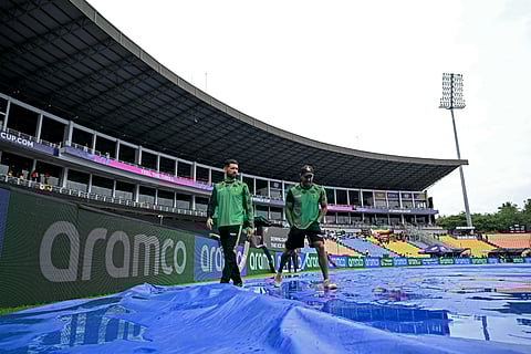 Zimbabwe's captain Sikandar Raza (L) and coach Dion Ebrahim inspect the covered pitch as rain delays the start of the 2026 ICC Men's T20 Cricket World Cup group stage match between Zimbabwe and Ireland at Pallekele International Cricket Stadium.