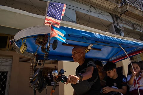 A driver steers his bicycle taxi decorated with US and Cuban flags in Havana, Cuba, Monday, Feb 16, 2026.