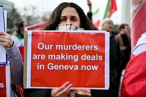 A protester holds a placard during a demonstration in front of United Nations office ahead of indirect nuclear talks between the United States and Iran in Geneva on February 17, 2026.