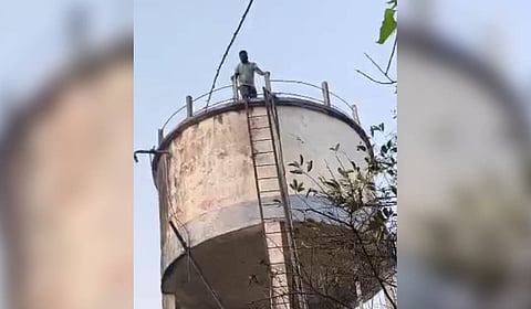 Former sarpanch of Arepally, Karunakar, climbs the overhead tank of the village demanding payment of pending bills in Arepally on Wednesday.