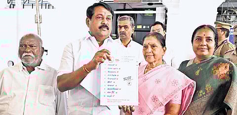 BJP state president Nainar Nagenthran posing with the report card outside the Assembly.