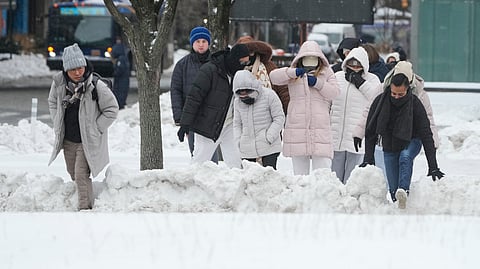 Pedestrians climb over snowbanks to try and cross the streets in New York, Monday, Jan. 26, 2026.