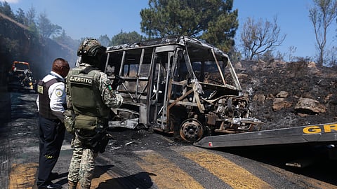 A soldier stands guard by a charred vehicle that was set on fire in Cointzio, Mexico, Sunday, Feb. 22, 2026, amid reports the Mexican Army killed Jalisco New Generation Cartel leader Nemesio Oseguera, known as "El Mencho."
