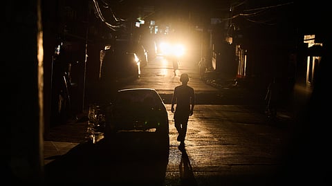 A man walks in a street during a blackout in Santo Domingo, Dominican Republic, Monday, Feb. 23, 2026.