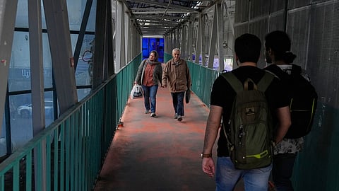 People walk across an overpass in downtown Tehran, Iran, Tuesday, Feb. 24, 2026.