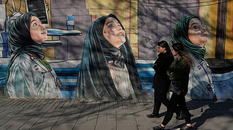 Women walk past a mural at a girls school at Enqelab-e-Eslami, or Islamic Revolution Street, in downtown Tehran, Iran, Wednesday, Feb. 25, 2026.