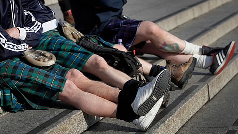 Scottish soccer fans wearing kilts sit on the steps in Trafalgar Square after attending a service to mark Armistice Day in London, Friday, Nov. 11, 2016.
