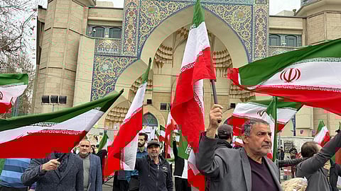 A group of men wave Iranian flags as they attend a demonstration in support of the government and against U.S. and Israeli strikes in Tehran.