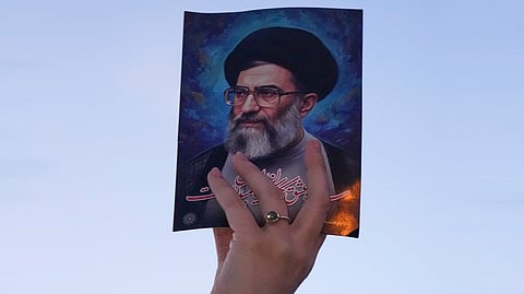 A government supporter holds up a picture of the Iranian Supreme Leader Ayatollah Ali Khamenei during a gathering after state TV officially announced the death of Khamenei in Tehran, Iran, Sunday, March 1, 2026.