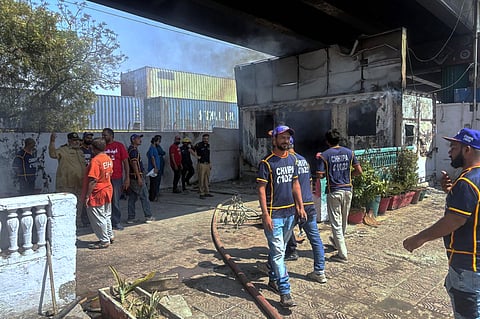 Police officers and rescue workers examine a burnt police post, which was set on fire by angry protestors close to the U.S. Consulate following protesters stormed the U.S. Consulate in Karachi, Pakistan, Sunday, March 1, 2026.