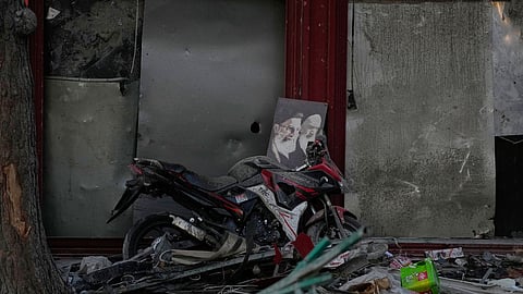 A poster of the late Supreme Leader Ayatollah Ali Khamenei, who was killed during the ongoing joint U.S.-Israeli military campaign, and the late Iranian Revolutionary founder Ayatollah Khomeini, right, lays on a motorcycle amid debris left by a strike in Tehran, Iran, Monday, March 2, 2026.
