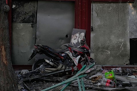 A poster of the late Supreme Leader Ayatollah Ali Khamenei, who was killed during the ongoing joint U.S.-Israeli military campaign, and the late Iranian Revolutionary founder Ayatollah Khomeini, right, lays on a motorcycle amid debris left by a strike in Tehran, Iran, Monday, March 2, 2026.