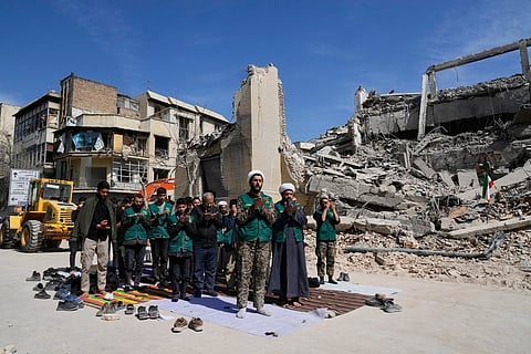A cleric leads a group of volunteers in prayer next to a police facility struck during the U.S.–Israeli military campaign in Tehran, Iran, Wednesday, March 4, 2026.