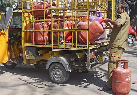 A worker seen unloading gas cylinders off an open-body truck in Bengaluru.