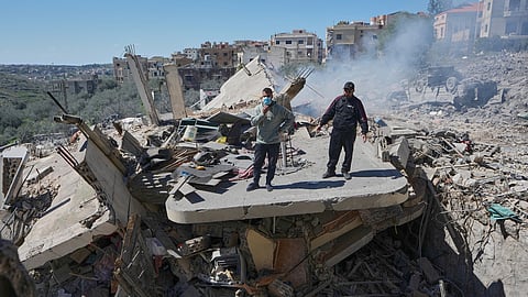 People stand on the wreckage of destroyed houses that were hit by Israeli airstrikes in Sir al-Gharbiyeh village south Lebanon, Sunday, March, 8, 2026.