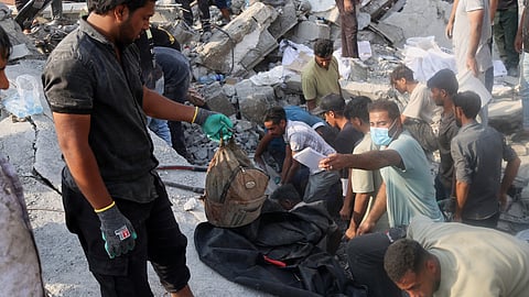 A man hold a children's backpack as rescue workers and residents search through the rubble in the aftermath of what Iranian officials said was an Israeli-U.S. strike on a girls' elementary school in Minab, Iran, Saturday, Feb. 28, 2026.