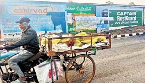 An old motorcycle illegally modified by attaching trolley, being ridden by a scrap dealer in Cuttack.