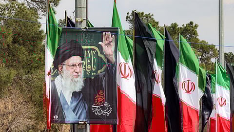 A banner depicting Iran's slain supreme leader Ayatollah Ali Khamenei is displayed before Iranian flags and black banners near graves of recently-buried people killed in US-Israeli airstrikes at Beheshta Zahra cemetery on the southern outskirts of Tehran on March 9, 2026.