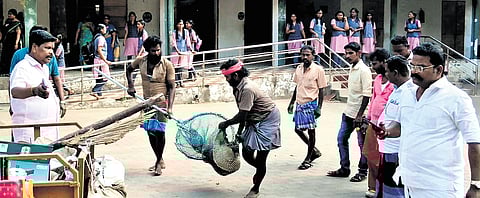 Municipality workers carry the stray dog that entered the school on Wednesday.