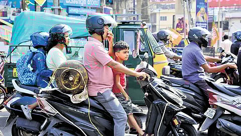 Amid fuel shortage and the rise in cooking gas prices, a customer is seen riding with his child seated in front and an empty gas cylinder tied to the back, heading to a gas refill centre. A scene from Kaloor in Kochi on Wednesday | A Sanesh