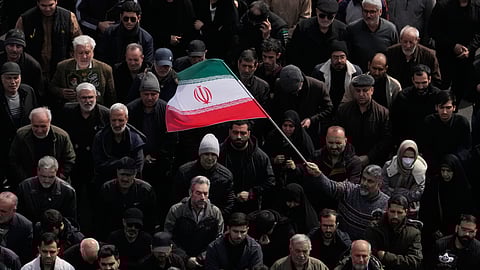 A man waves an Iranian flag as a crowd attends the funeral procession for senior Iranian military officials and civilians killed during the U.S.-Israel campaign in Tehran, Iran, Wednesday, March 11, 2026.