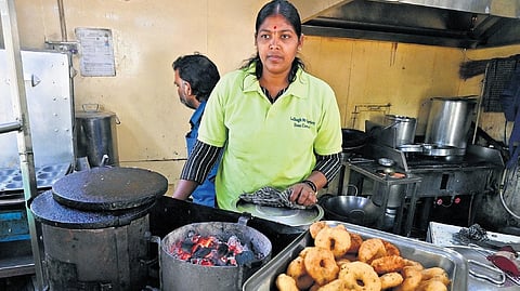 Staffers at 99 Varieties Dosa Corner near Lalbagh prepare snacks using a charcoal stove due to shortage of commercial LPG cylinders in Bengaluru on Wednesday.