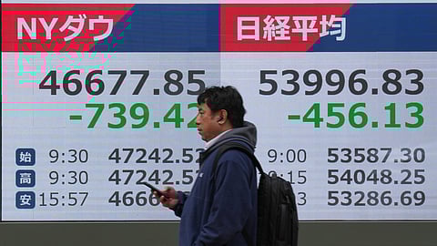 A person walks in front of an electronic stock board showing Japan's Nikkei index at a securities firm Friday, March 13, 2026, in Tokyo.