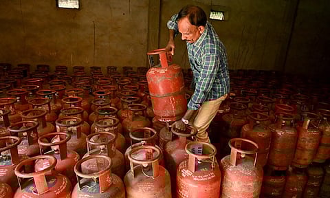 A worker sorts empty cylinders inside a godown amid LPG cylinder shortage.