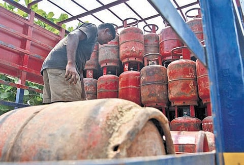 A worker loads empty LPG cylinders into a truck in Vijayawada.