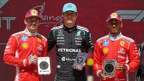 Mercedes driver George Russell, center, of Britain poses with Ferrari driver Charles Leclerc, left, second place, of Monaco and Ferrari driver Lewis Hamilton, third place, of Britain after the Sprint Race of the Chinese Formula One Grand Prix on March 14, 2026.