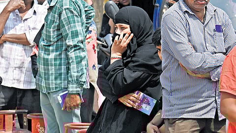 Residents wait to collect LPG cylinders at a ground near Shivajinagar in Bengaluru on Monday