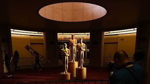People look on as workers install Oscar statues Saturday, March 14, 2026, at the Dolby Theatre in Los Angeles, in preparation for Sunday's 98th Academy Awards ceremony.