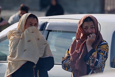 Two women watch as rescue workers and officials inspect the site of a late-Monday airstrike at a drug rehabilitation hospital in Kabul, Afghanistan, Tuesday, March 17, 2026.