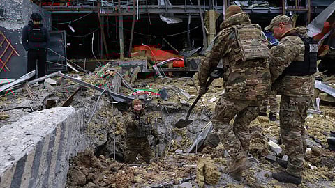 Sappers examine the site of a Russian missile strike which hit a post office storehouse in Zaporizhzhia, Ukraine, Tuesday, March 17, 2026.