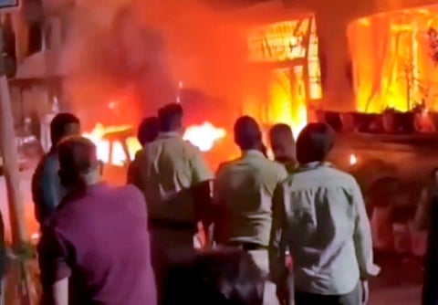 People gather as a house is engulfed in flames after a fire broke out, in Indore, Madhya Pradesh, Wednesday, March 18, 2026. Seven persons were killed in the incident, officials said.