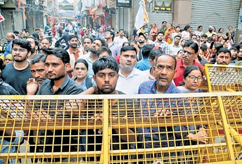 Locals look on as fire personnel extinguish the fire that broke out in a four-storey building in southwest Delhi’s Palam area.