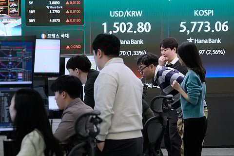 Currency traders watch monitors near a screen showing the Korea Composite Stock Price Index (KOSPI), right, and the foreign exchange rate between U.S. dollar and South Korean won at the foreign exchange dealing room of the Hana Bank headquarters in Seoul, South Korea, Thursday, March 19, 2026