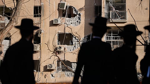 People look at residential buildings damaged by an Iranian missile strike in Arad, southern Israel, Sunday, March 22, 2026.