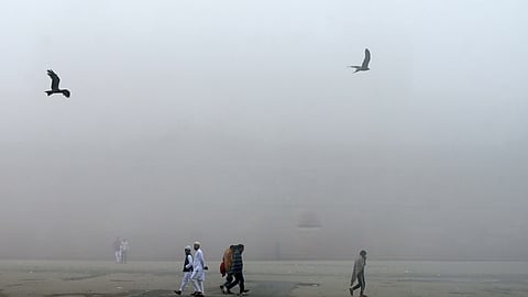 People seen walking at Red Fort amid dense fog in New Delhi on Saturday.