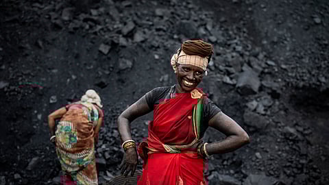 FILE- A laborer smiles as she takes a break from loading coal into a truck in Dhanbad, an eastern Indian city in Jharkhand state, on Sept. 24, 2021.