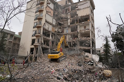 Iranian firefighters use an excavator to clear rubble from a residential building that was hit in an earlier U.S.-Israeli strike in Tehran, Iran, Monday, March 23, 2026.