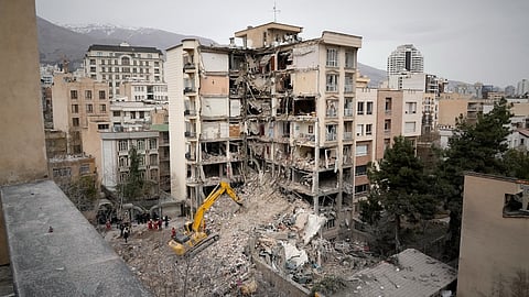 Iranian Red Crescent emergency workers use a bulldozer to clear rubble from a residential building that was hit in an earlier U.S.-Israeli strike in Tehran, Iran, Monday, March 23, 2026.