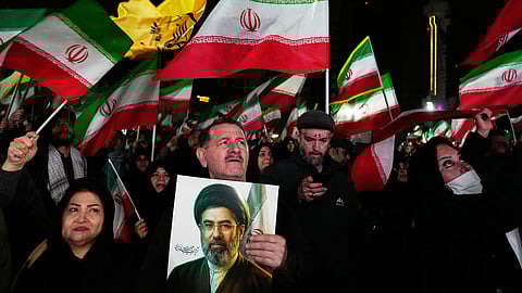 Pro-government supporters wave national flags as one of them holds a picture of the Supreme Leader Ayatollah Mojtaba Khamenei during a rally in a square in western Tehran, Iran, Wednesday, March 25, 2026.