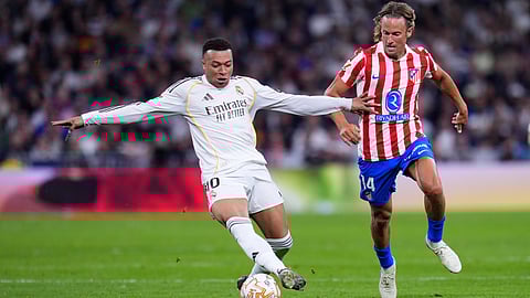 Real Madrid's Kylian Mbappe, left, and Atletico Madrid's Marcos Llorente challenge for the ball during the Spanish La Liga soccer match between Real Madrid and Atletico Madrid in Madrid, Spain, Sunday, March 22, 2026.