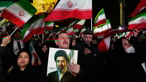 Pro-government supporters wave national flags as one of them holds a picture of the Supreme Leader Ayatollah Mojtaba Khamenei during a rally in a square in western Tehran, Iran, Wednesday, March 25, 2026.