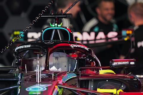 Mercedes driver George Russell of Britain's car is seen in the garage as mechanics talk nearby in Suzuka, central Japan.
