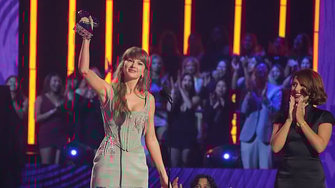 Taylor Swift accepts the award for Pop Album of the Year during the IHeartRadio Music Awards on Thursday, March 26, 2026, at the Dolby Theatre in Los Angeles. Raye looks on from right.