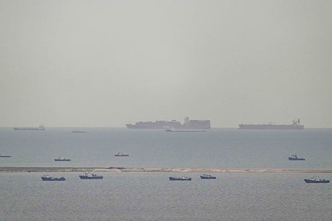 Fishing boats dot the sea as cargo ships, in the background, sail through the Arabian Gulf toward the Strait of Hormuz off the United Arab Emirates, Friday, March 27, 2026.