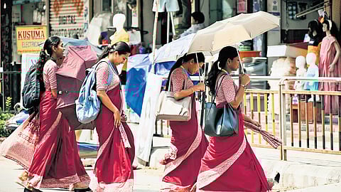 Women use umbrellas to shield themselves from the heat while crossing a road in Karimnagar on Friday