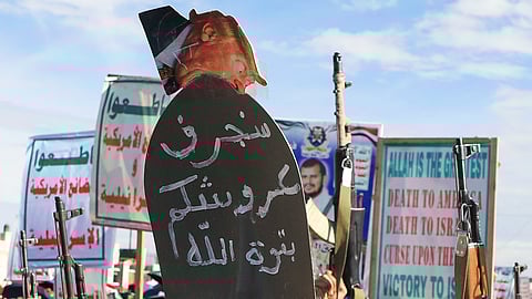Houthi supporters shout slogans during a rally against Israel and the United States' war in Iran, in Sanaa, Yemen, Friday, March 27, 2026. The sign reads in Arabic, "We will remove your throne."